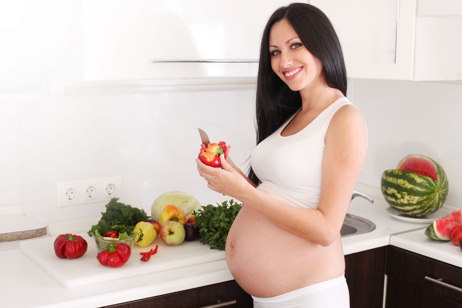 Беременная девушка режет овощи