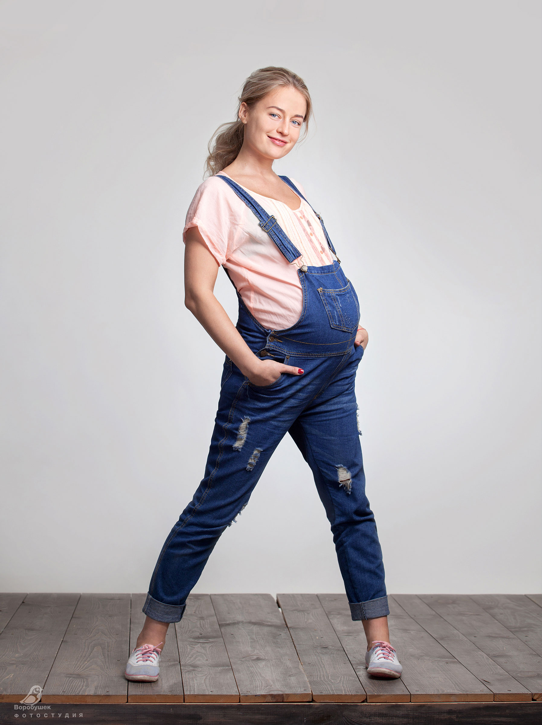 Беременная девушка в джинсовом комбинезоне