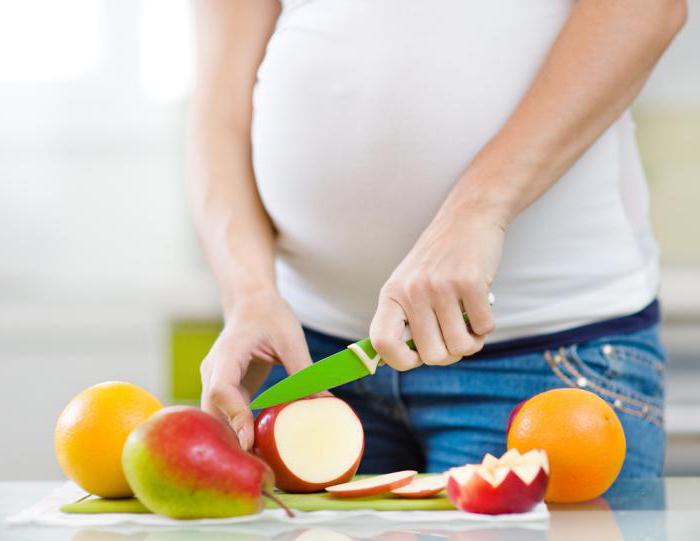 Беременная девушка режет фрукты